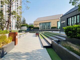 Modern outdoor common area with green spaces and seating in a residential building complex