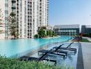 Luxurious outdoor swimming pool with lounging chairs and modern residential building