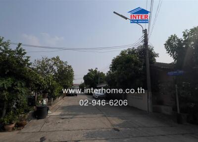 Exterior view of the property with lush greenery and a real estate sign