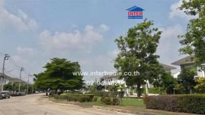 View of a residential street with houses and lush greenery under a clear sky