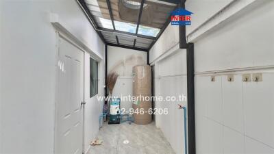 Narrow corridor or storage space in a property featuring storage cabinets and tiled flooring