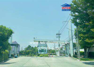 Street view of a modern residential building with clear blue sky and lush greenery