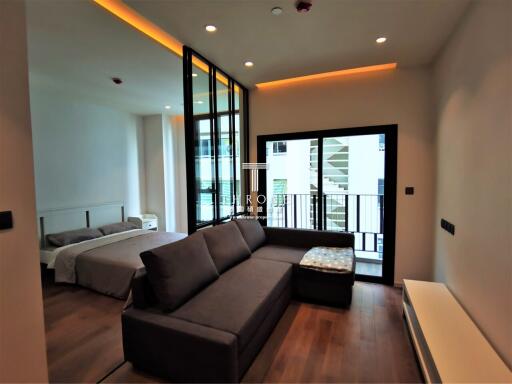 Spacious modern bedroom with a comfortable sofa and access to a balcony