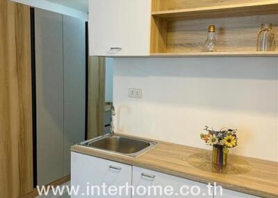 Modern kitchenette with wooden shelves and white cabinets