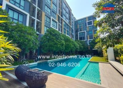 Luxurious apartment building with a large outdoor swimming pool surrounded by lush greenery