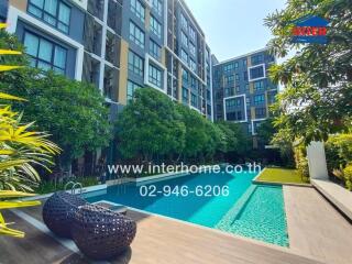 Luxurious apartment building with a large outdoor swimming pool surrounded by lush greenery