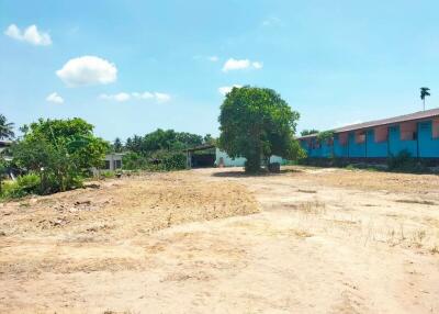 Spacious vacant land with surrounding buildings and clear blue sky