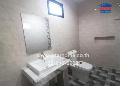 Modern bathroom with neutral tiled walls, sink, and toilet