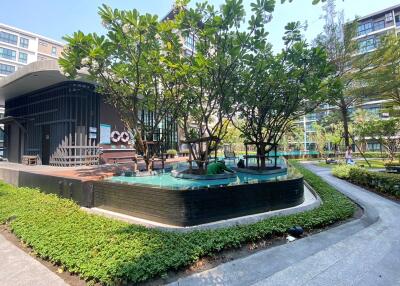 Modern residential building exterior with landscaped green space and water feature