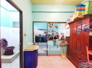 Compact bathroom with visible laundry area and kitchen in the background