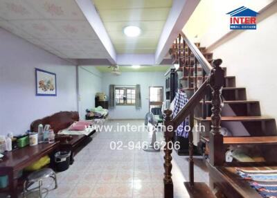 Spacious living room with traditional wooden staircase and tiled floor