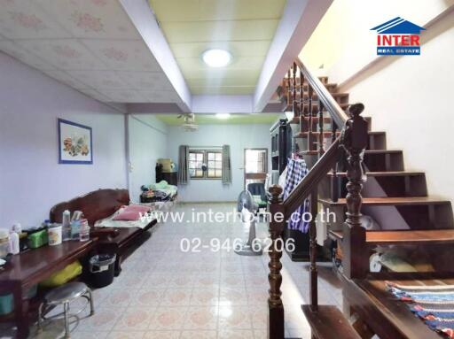 Spacious living room with traditional wooden staircase and tiled floor