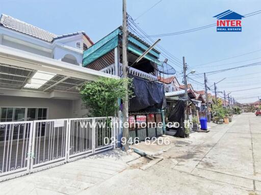 Street view of a residential house with visible branding and contact details