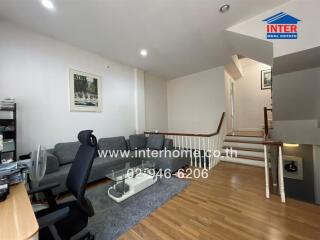 Spacious and well-lit living room with modern furnishings and staircase