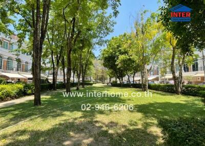 Lush green common area with trees and lawn in a residential complex
