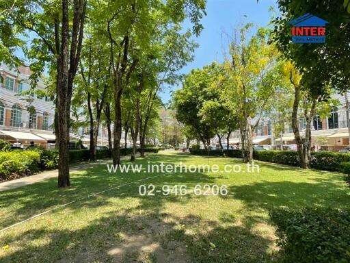 Lush green common area with trees and lawn in a residential complex