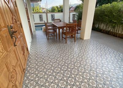 Spacious covered porch area with traditional tile flooring and wooden furniture