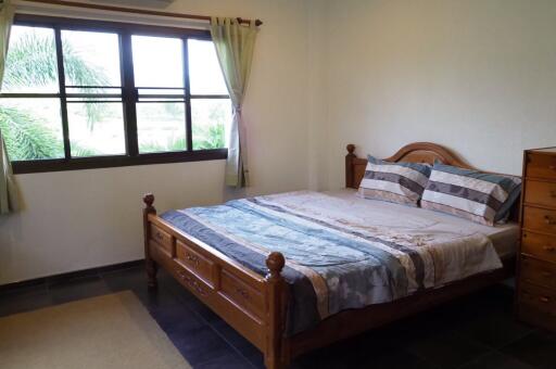 Spacious bedroom with large window and wooden furniture