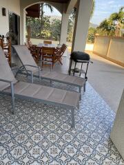 Spacious patio area with decorative tile flooring and outdoor furniture overlooking a scenic view