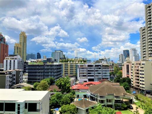Panoramic cityscape showing a blend of modern high-rises and traditional residential buildings under a clear blue sky