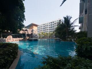 Spacious outdoor swimming pool surrounded by tropical plants near residential buildings