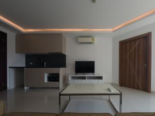 Modern living room with integrated kitchen, featuring contemporary furniture and ambient lighting
