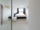 Modern minimalist bedroom with a large bed and ample natural light