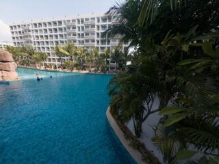 Luxurious resort-style outdoor pool with lush landscaping and residential building in the background