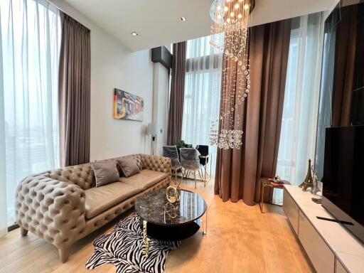 Elegant living room with modern furnishings, including a tufted sofa and stylish glass coffee table