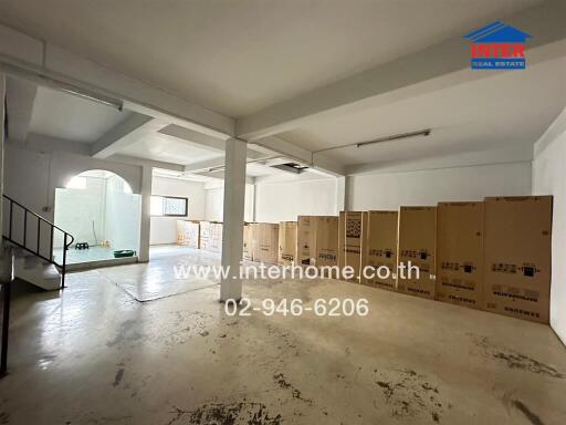 Spacious empty commercial space with large boxes and a staircase