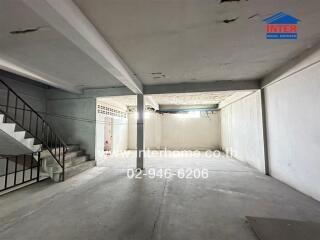 Spacious empty garage with staircase and white walls