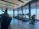 Modern gym with cardio machines and weights overlooking cityscape through large windows