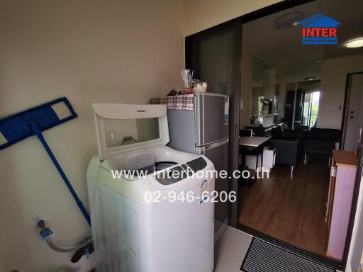Compact laundry area with modern appliances leading to living room