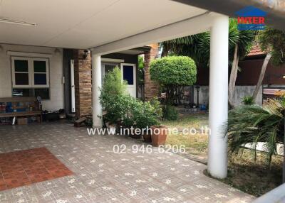 Covered carport area of a home with paved flooring and garden view