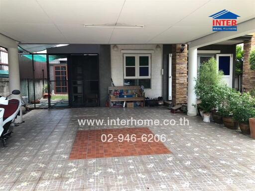 Covered outdoor area with tiled flooring and seating space beside a house