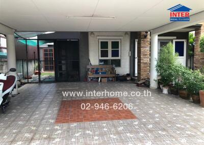 Covered outdoor area with tiled flooring and seating space beside a house