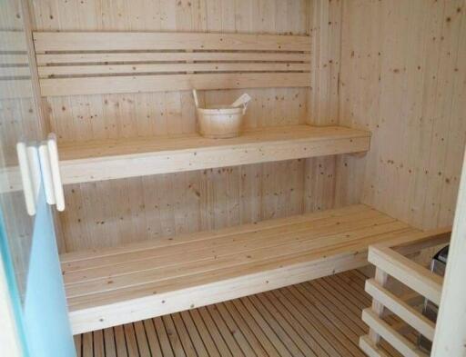 Interior view of a modern wooden sauna with benches and accessories