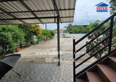 Spacious covered patio area with tiled flooring, leading to a large, open garden