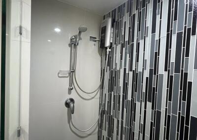 Modern bathroom with wall-mounted shower and stylish black and white tiles