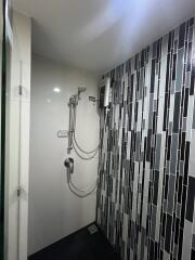 Modern bathroom with wall-mounted shower and stylish black and white tiles