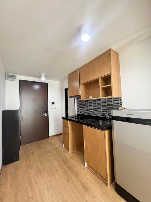 Compact modern kitchen with wood cabinets and black countertops