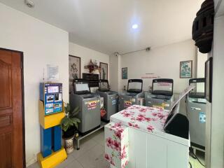 Spacious communal laundry room with multiple washing machines and decorative touches