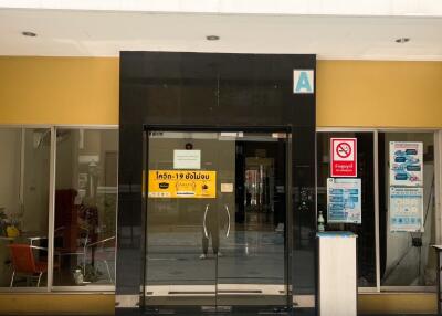 Modern building entrance with glass doors and pandemic safety signage