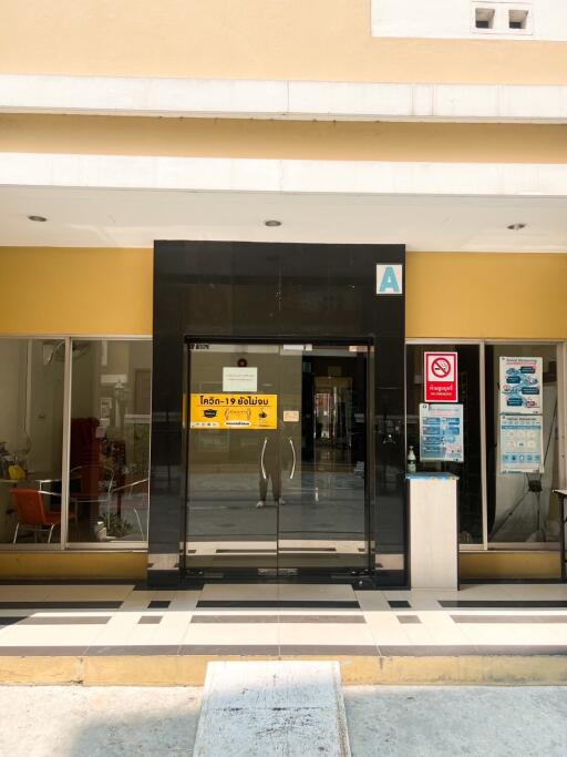 Modern building entrance with glass doors and pandemic safety signage
