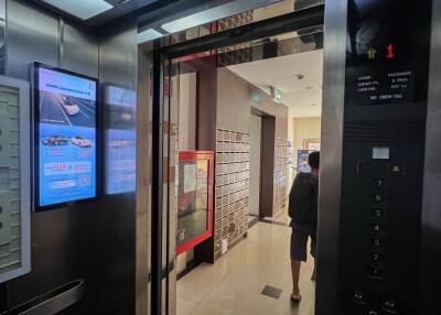 Modern building lobby with elevator, digital display and decorative elements