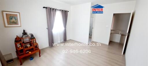 Spacious living room with natural light and adjacent kitchen entrance