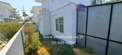 White two-story corner house with a fenced yard and landscaping