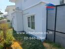 White two-story corner house with a fenced yard and landscaping