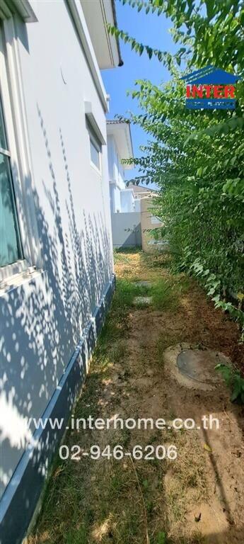 Exterior side view of a white residential building with a narrow garden