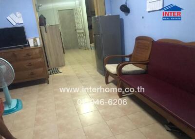 Spacious furnished living room with tiled flooring, comfortable seating, and essential appliances